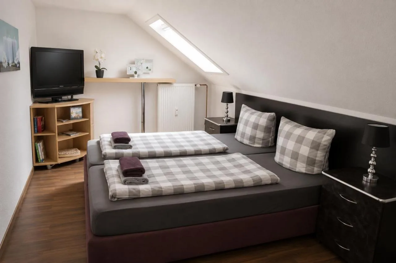Zimmer mit Doppelbett, Flachbild-TV und Regal unter der Dachschräge in Augustdorf