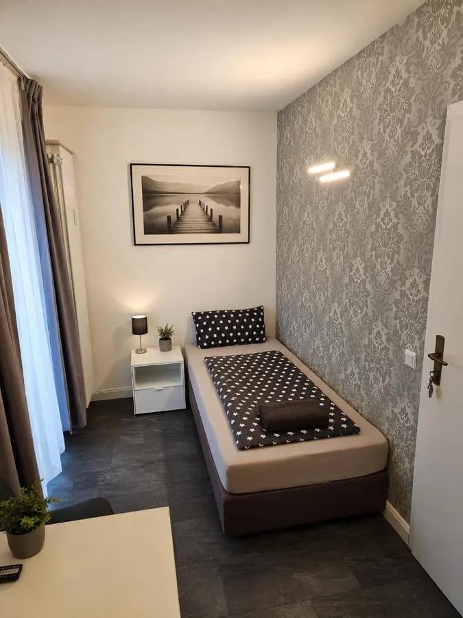 Einzelzimmer mit Bett und Nachttisch in Augustdorf